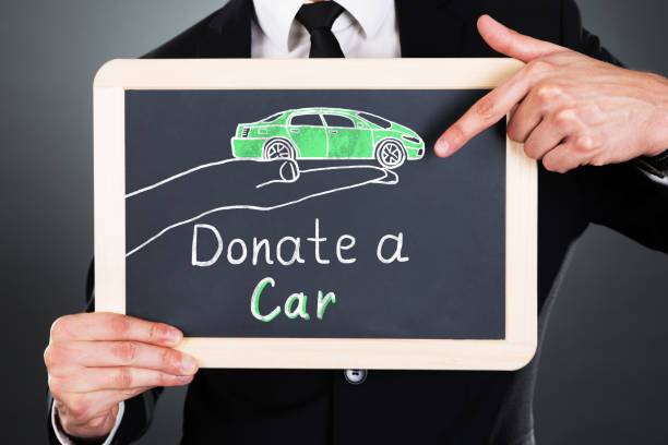 Man holding a donate your car sign.